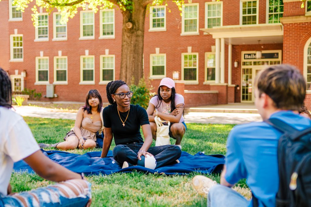 Students chatting while sitting on lawn in the Quad